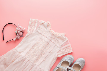 Girls' fashion background in pastel pink, lace dress, sparkly shoes, flower headband, flat lay, top view, toned photo, copy space for text, selective focus