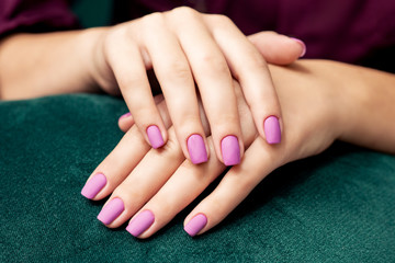 Perfect purple matte manicure on the woman's nails, close up.