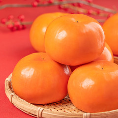 Fresh beautiful sliced sweet persimmon kaki isolated on red table background and bamboo sieve, Chinese lunar new year design concept, close up.