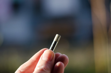 A man holds a small bolt in his hand