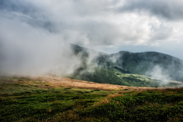 Naklejka na ściany i meble Foggy mountain range during a stormy summer day