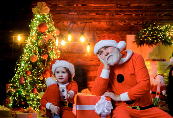 Christmas time. Family holidays. Christmas presents. Christmas boy in santa costume with Santa Claus. Happy holidays. Santa Claus man and little Santa boy with Christmas decoration. Happy New Year.