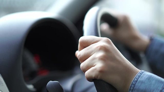 man driving car in day time, hand on steering wheel, shallow depth of field