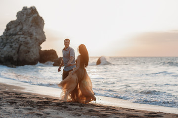 Couple in love at dawn by the sea. Honeymoon trip. Man and woman traveling. Happy couple by the sea view from the back. Man and woman holding hands. Couple in love on vacation. Follow me. Couple on a 