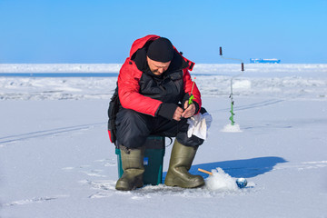 Fototapeta na wymiar Man ice fishing on a frozen Gulf of Finland