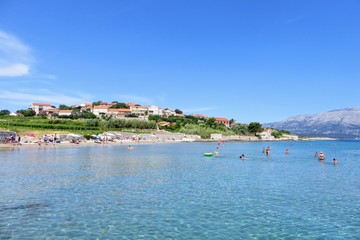 Fototapeta premium Locals and tourists enjoying a beautiful summer day along the sandy beaches of Lumbarda Beach on Korcula Island, Croatia