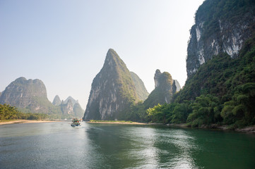 Boat on Li river cruise and karst formation mountain landscape in the fog between Guiling and Yangshuo, Guangxi province, China - obrazy, fototapety, plakaty