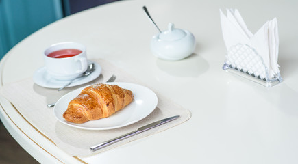 Fruit tea and delicious fresh croissant on the table in a cozy coffee shop
