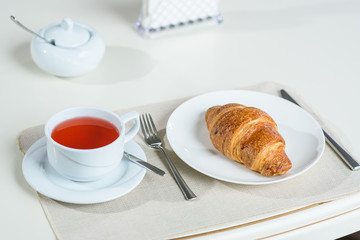 Fruit tea and delicious fresh croissant on the table in a cozy coffee shop