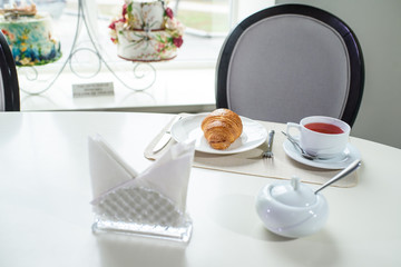 Fruit tea and delicious fresh croissant on the table in a cozy coffee shop