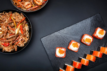 rolls and noodles with shrimp on a black background