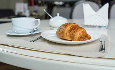 Fruit tea and delicious fresh croissant on the table in a cozy coffee shop