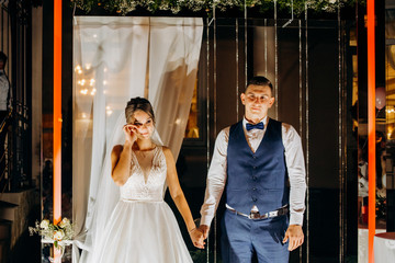 Evening wedding ceremony. The bride and Groom are on the background of the wedding arch