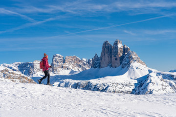 active senior woman snowshoeing  under the famous Three Peaks, Dolomites  near village of Toblach,...