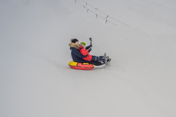 Fototapeta na wymiar mom son ride on an inflatable winter sled tubing. Winter fun for the whole family