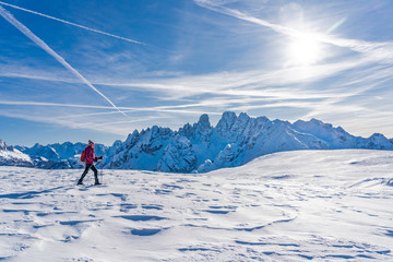 Fototapeta na wymiar active senior woman snowshoeing under the famous Three Peaks from Prato Piazzo up to the Monte Specie in the three oeaks Dolomites area near village of Innichen, South Tyrol, Italy