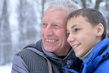 Smiling senior man and boy standing outdoors in winter