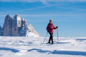 Fototapeta na wymiar active senior woman snowshoeing under the famous Three Peaks from Prato Piazzo up to the Monte Specie in the three oeaks Dolomites area near village of Innichen, South Tyrol, Italy