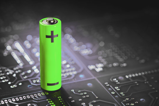A lithium-ion battery stands on the background of electronic circuit boards.