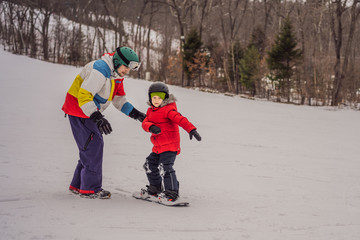 Snowboard instructor teaches a boy to snowboarding. Activities for children in winter. Children's winter sport. Lifestyle