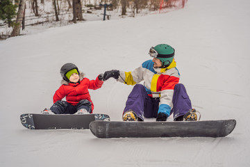 Fototapeta na wymiar Snowboard instructor teaches a boy to snowboarding. Activities for children in winter. Children's winter sport. Lifestyle