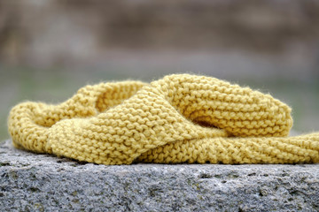 Knitted yellow scarf on a stone closeup 1