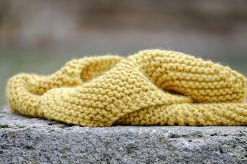 Knitted yellow scarf on a stone closeup 2