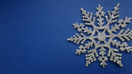 A fragment of a decorative snow star on a dark blue background . Creative Christmas concept. Flat lay.