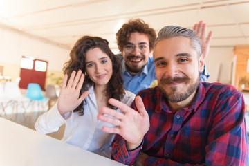 Portrait of happy successful creative team waving hello. Business colleagues in casual meeting in...