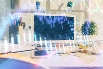 Stock market graph on background with desk and personal computer. Double exposure. Concept of financial analysis.