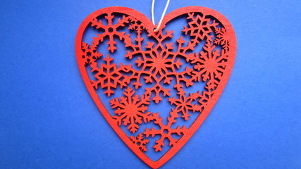 Cut out in wood a red ornamental heart on a string with a bead on a blue background. Flat lay.  Creative gift idea