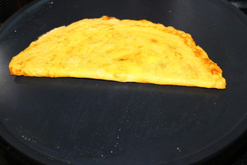 Moong dal cheela getting cooked on a non stick electric tawa