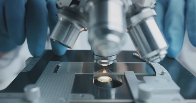 Close up shot of the scientist studies examining of test sample under the microscope in laboratory.