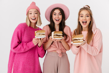 Image of three girls in pink clothes smiling and holding birthday cakes
