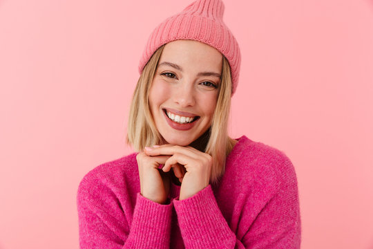 Image of positive beautiful blonde girl wearing hat and sweater smiling