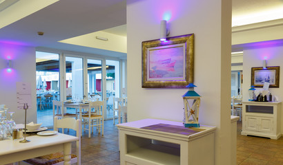 evening interior of the restaurant with white furniture and tables in resort European hotel, Greece