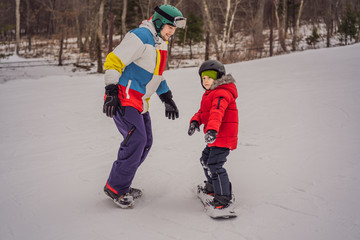 Snowboard instructor teaches a boy to snowboarding. Activities for children in winter. Children's winter sport. Lifestyle