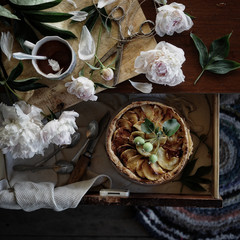 still life with apple pie and peonies flowers on an old table top view