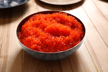Fresh red caviar in bowl on wooden table