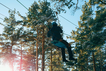Man on a rope town (bridge) in an adventure rope park. Winter sport, leisure and outdoor games