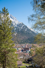 view to tourist resort Mittenwald, village church and karwendel alps with snow, upper bavaria. fir tree and birch