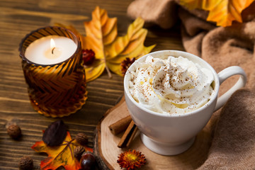Hot coffee cup with cream and cinnamon spice, hot chocolate autumn cozy setting with soft blanket
