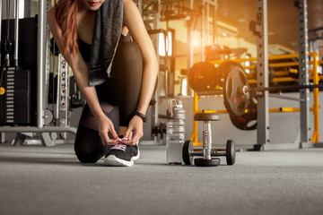 Fototapeta premium Fitness woman tying shoelaces before exercise workout at gym. Healthy and lifestyle concept.