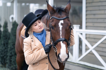 A 50 year old woman rides a horse. Walking with a horse. He is engaged in hippotherapy. A woman is wearing a trendy derby costume.