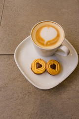 A Cup of hot latte art coffee with cookies