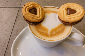 A Cup of hot latte art coffee with cookies