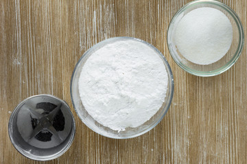 Sugar powder, sugar and coffee grinder on the wooden background