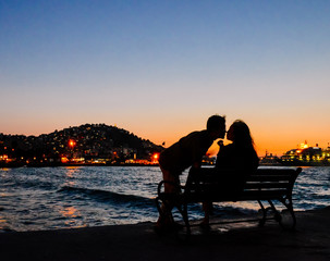 silhouette of young couple kissing by sea