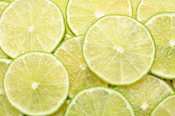 Many fresh juicy lime slices as background, top view