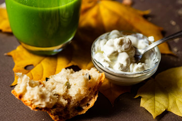 Cottage cheese, bread and matcha tea on yellow leaves.